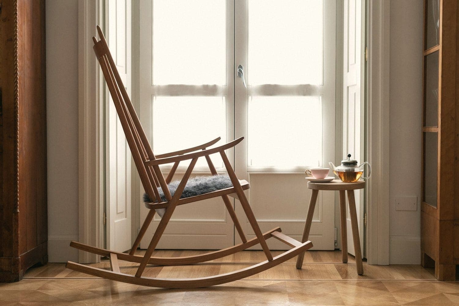 A wooden rocking chair beside a tall window