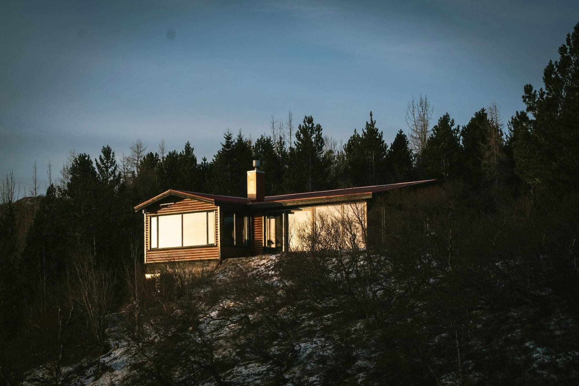 A cabin with lit windows among dark pines